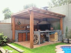 an outdoor kitchen with a grill and hot tub in the middle of a backyard area