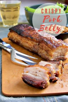 a wooden cutting board topped with meat next to a knife and fork