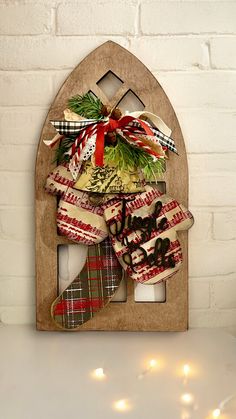 a christmas stocking holder with stockings and lights in front of a white brick wall