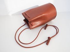 "Classic yet contemporary bucket bag, combined a minimalism and functional. The body made from Italian vegetan leather, using leather cord for the shoulder strap. The shoulder strap is adjustable, able to enjoy this bag for 3 ways as a crossbody bag, one-shoulder bag and handbag. Has a card sized inside pocket. Approximate Dimensions: W 4.75\" x H 8\" x D 4.75\" W 12cm x H 20cm x D 12cm Inside pocket W 3.50\" x H 3.50\" W 9.5cm x H 9.5cm - 100% Vegetable tanned leather (body) - Genuine leather c Modern Cognac Bucket Bag With Adjustable Strap, Minimalist Bucket Shoulder Bag With Detachable Strap, Minimalist Office Bucket Bag With Adjustable Strap, Minimalist Bucket Shoulder Bag With Leather Handles, Minimalist Bucket Shoulder Bag With Adjustable Strap, Daily Use Crossbody Bucket Bag With Leather Strap, Leather Bucket Bag With Long Strap For Everyday Use, Daily Use Leather Strap Crossbody Bucket Bag, Leather Strap Crossbody Bucket Bag For Daily Use