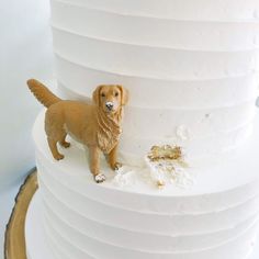 a dog figurine standing on top of a white tiered cake with icing