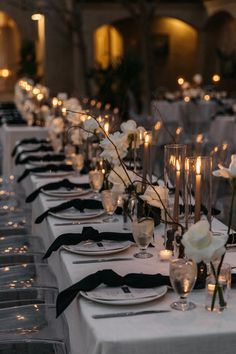 a long table is set up with white flowers and candles for an elegant wedding reception