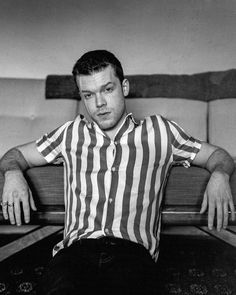 a black and white photo of a man sitting on a couch with his arms crossed