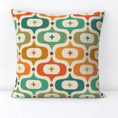 an orange and green pillow on a white surface