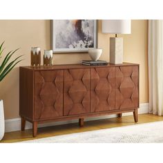 a brown sideboard sitting on top of a wooden floor next to a lamp and vase