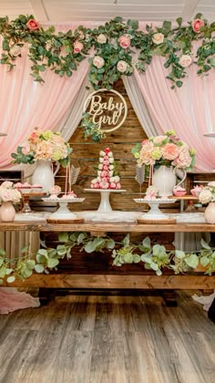 a dessert table with flowers and greenery on it at a baby girl shower party