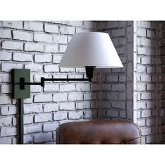 a lamp that is on the side of a brick wall next to a leather chair