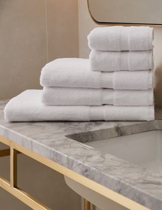 a stack of white towels sitting on top of a bathroom counter