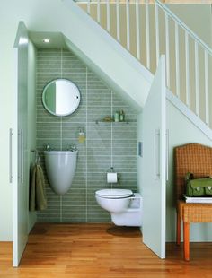 a white toilet sitting next to a wooden floor under a stair case in a bathroom