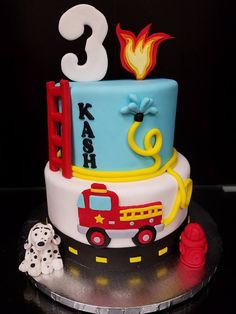 a birthday cake with a firetruck and dog on the side is decorated in blue, yellow and red