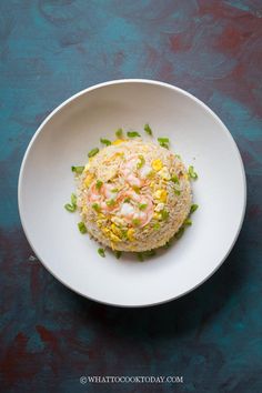 a white plate topped with rice covered in shrimp and veggies on top of it