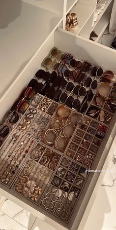 an open drawer filled with lots of different types of glasses and jewelry on display in a store