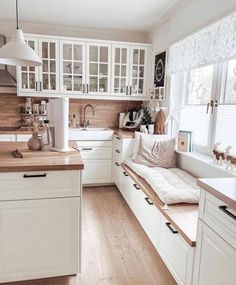 a kitchen filled with lots of white cabinets and counter top space next to a window