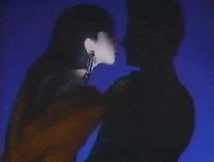 a man and woman standing next to each other in front of a blue background with the silhouette of two people