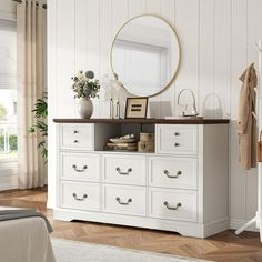 a white dresser with drawers and a mirror above it in a room that has wood floors