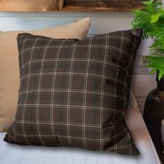 a pillow sitting on top of a white bed next to a potted green plant