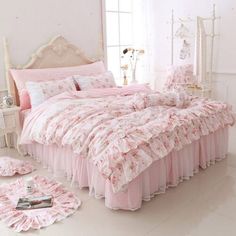 a bed with pink bedspread and matching comforters in a white room next to a window