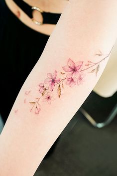 a woman's arm with flowers on it, and the tattoo is done in pink ink