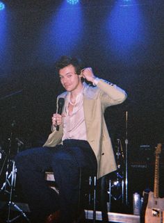 a man sitting on top of a chair holding a microphone