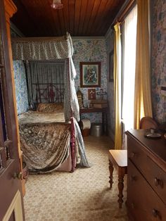 an old fashioned bedroom with floral wallpaper and canopy bed in the middle of it