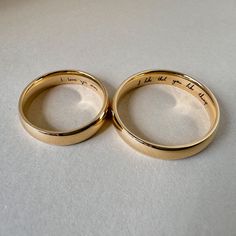 two gold wedding rings with handwriting on them