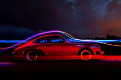 a red car with neon lights on it's side in front of dark clouds