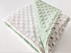 two white and green blankets sitting on top of each other