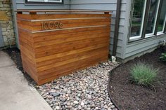 a large wooden box sitting on top of a gravel covered ground next to a house