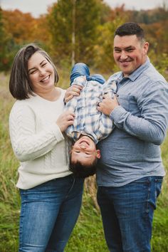 a man and woman holding a young boy in their arms while they smile at the camera