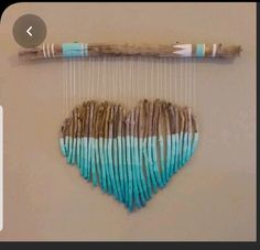 a piece of art made out of wood sticks and yarn with a heart on it