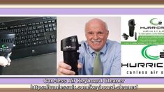 an old man holding a microphone in front of a computer keyboard and other electronic equipment