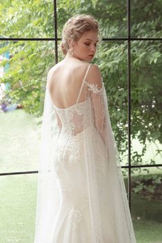 a woman in a wedding dress with a veil on her head is looking out the window