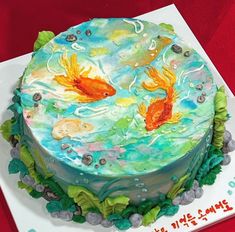 there is a cake decorated with two goldfishs in the water and green leaves