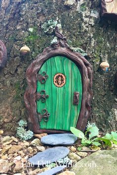 a small green door sitting in the middle of a tree stump next to some rocks