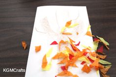 a paper plate with orange and yellow leaves on it next to a white cutting board