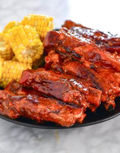 bbq ribs and corn on the cob with barbecue sauce in a black plate