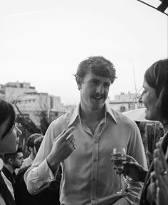 black and white photograph of two men talking to one another while holding wine glasses in their hands