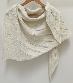 a white knitted shawl hanging on a wooden hanger