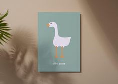 a card with a duck on it next to a potted plant and a wall