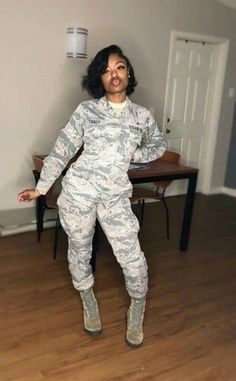 a woman in camo jumpsuits standing on the floor with her arms outstretched