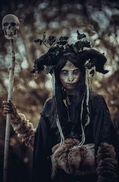 a woman dressed as a skeleton holding a stick and wearing a wreath on her head