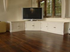 an empty living room with a flat screen tv on the wall and white cabinetry