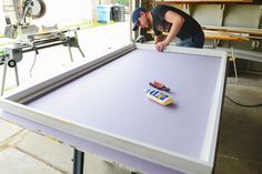 a man is working on some kind of art project in the garage with his tools