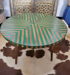 a green and pink table sitting on top of a cowhide rug