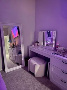 a bedroom with purple walls and furniture in the room, including a dressing table that has two stools on it