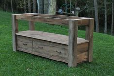 a wooden bench sitting on top of a lush green field next to a tall tree