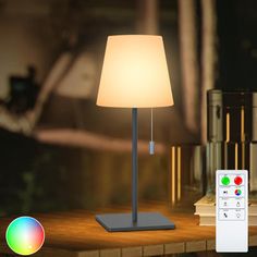 a lamp that is on top of a table next to a remote control and some books