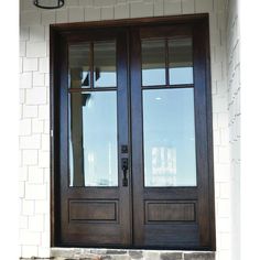 two brown double doors with glass and brick wall