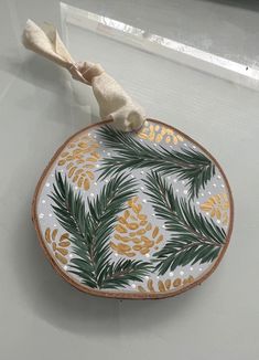 a decorative plate with pine cones and leaves on it, sitting on a counter top