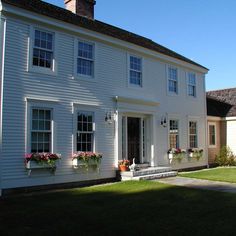 a large white house with flowers in the window boxes